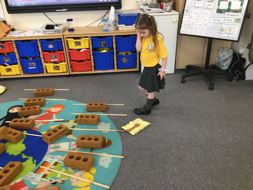 A Nursery child looking at objects on the floor.