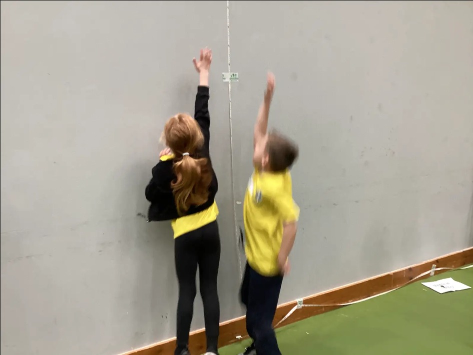 2 children jumping with an arm up